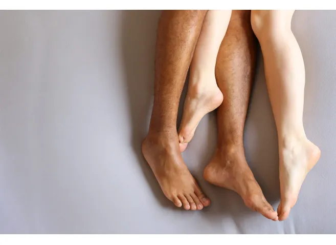 Legs of interracial couple in bed - copy space