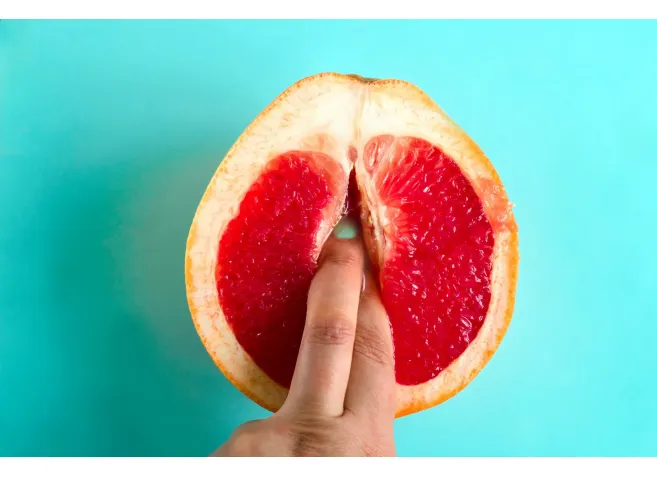 two fingers in a grapefruit isolated on a blue background top view sex concept