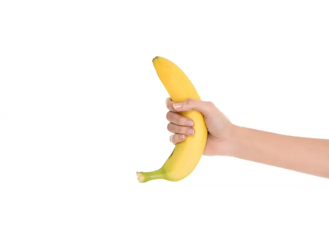 cropped shot of woman holding fresh banana in hand isolated on white