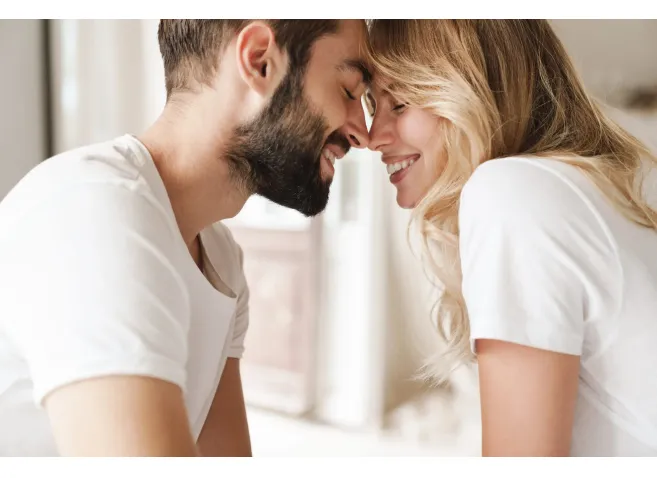 Beautiful happy young couple relaxing on bed at home, embracing